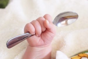 銀のスプーンを握る赤ちゃん